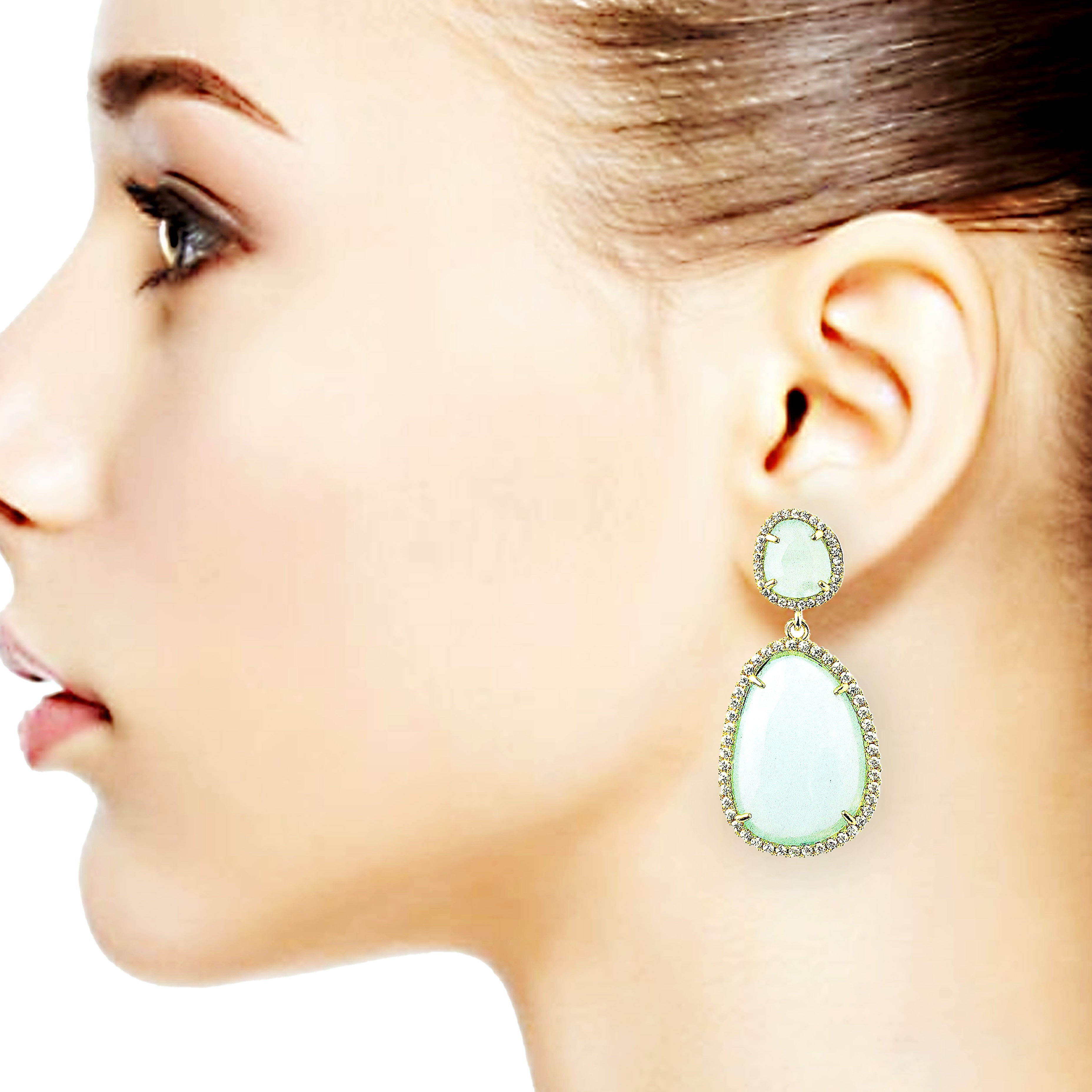 Close-up of a woman wearing a light green teardrop earring on a white background