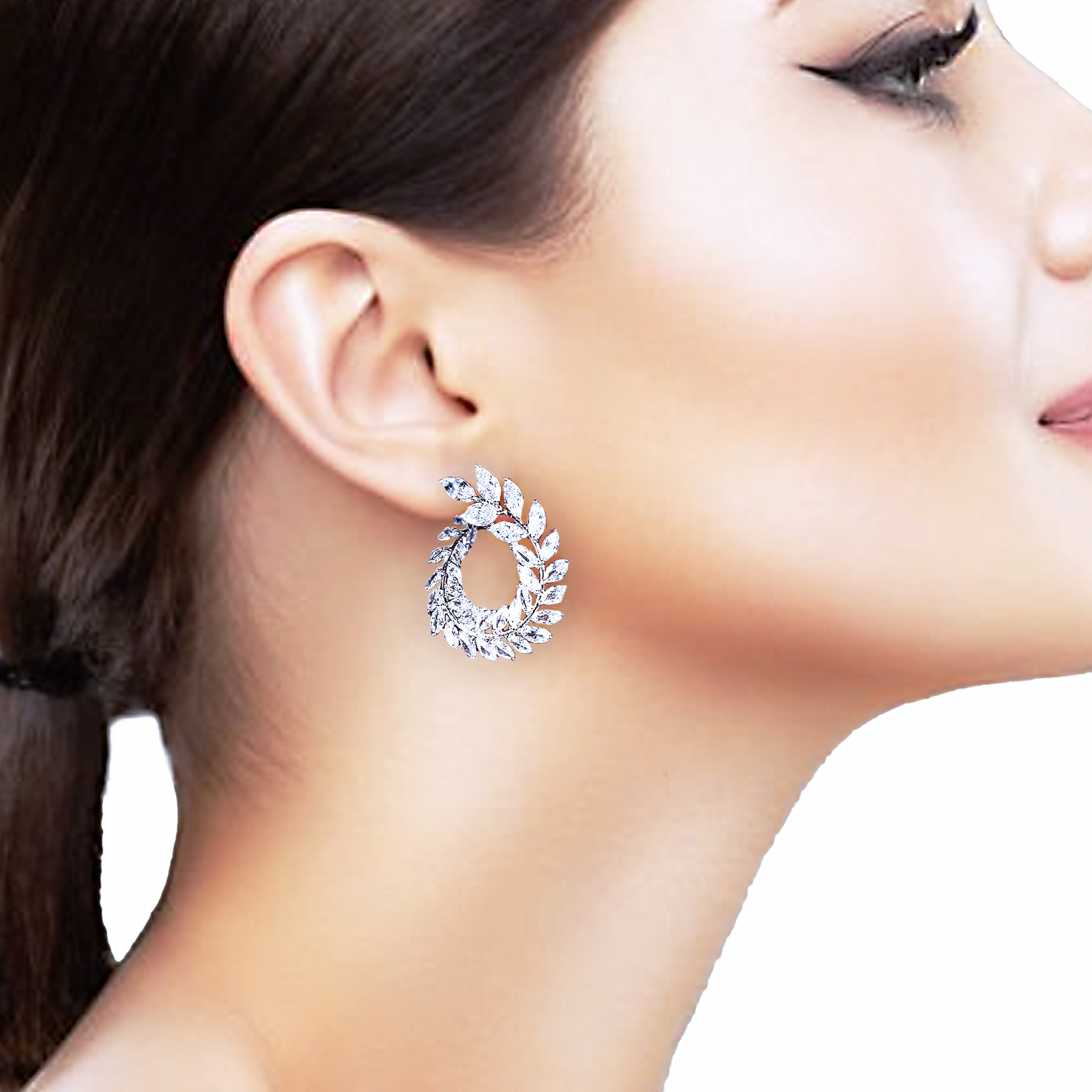 Close-up of a woman wearing a silver hoop earring with clear stones on a white background