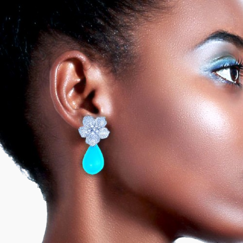 Close-up of a woman wearing a blue teardrop earring with a floral top.