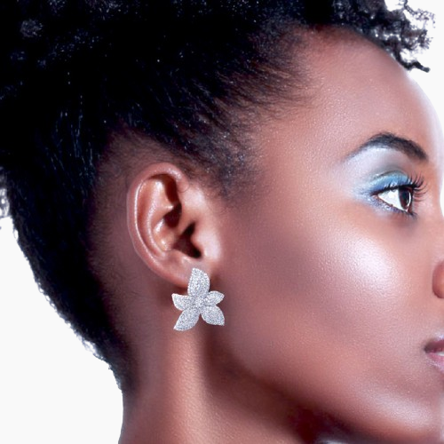 Close-up of a woman wearing a silver flower-shaped earring with a blurred background