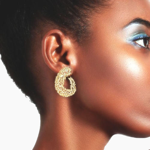 Close-up of a woman wearing gold hoop earrings with a neutral background