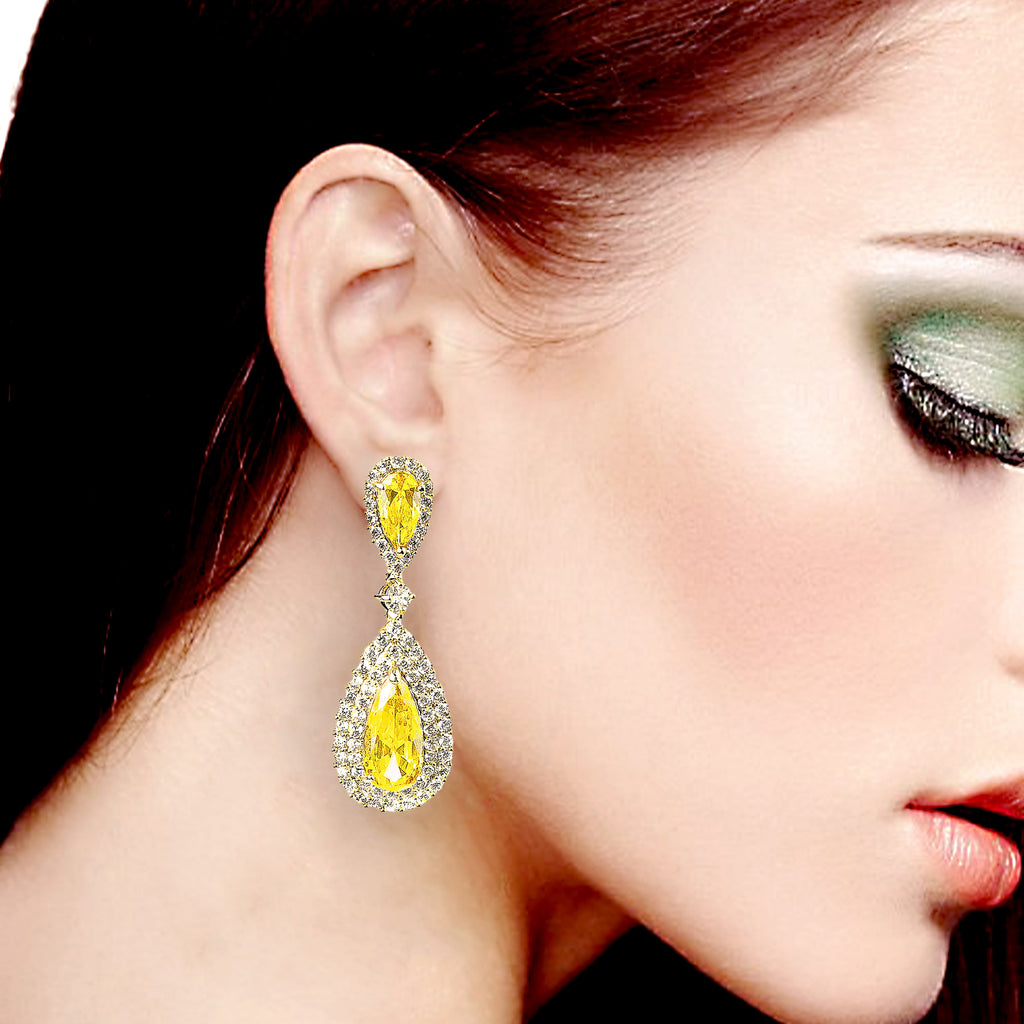Close-up of a woman wearing yellow teardrop earrings with a blurred background