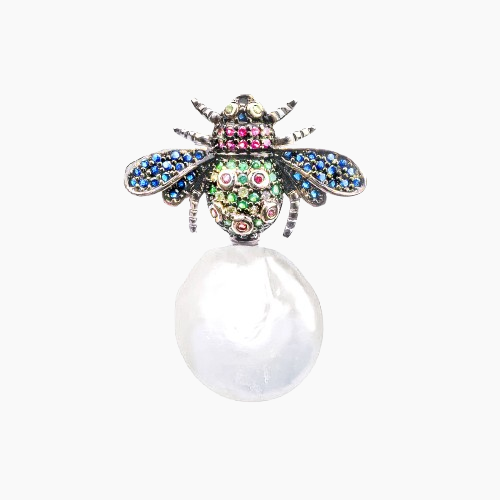 Decorative bee-shaped object with colorful gemstones on a white background