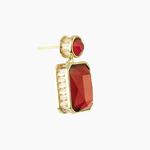 Gold earring with red gemstone on a white background