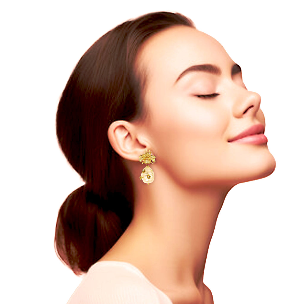 Woman wearing gold earrings with a plain background