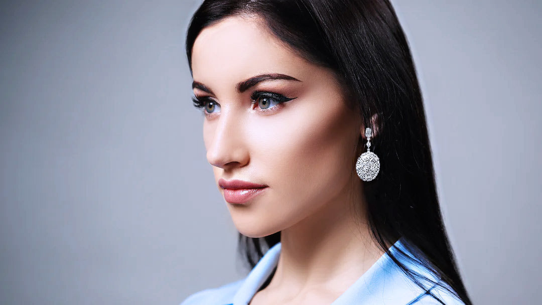 Woman wearing silver earrings against a gray background